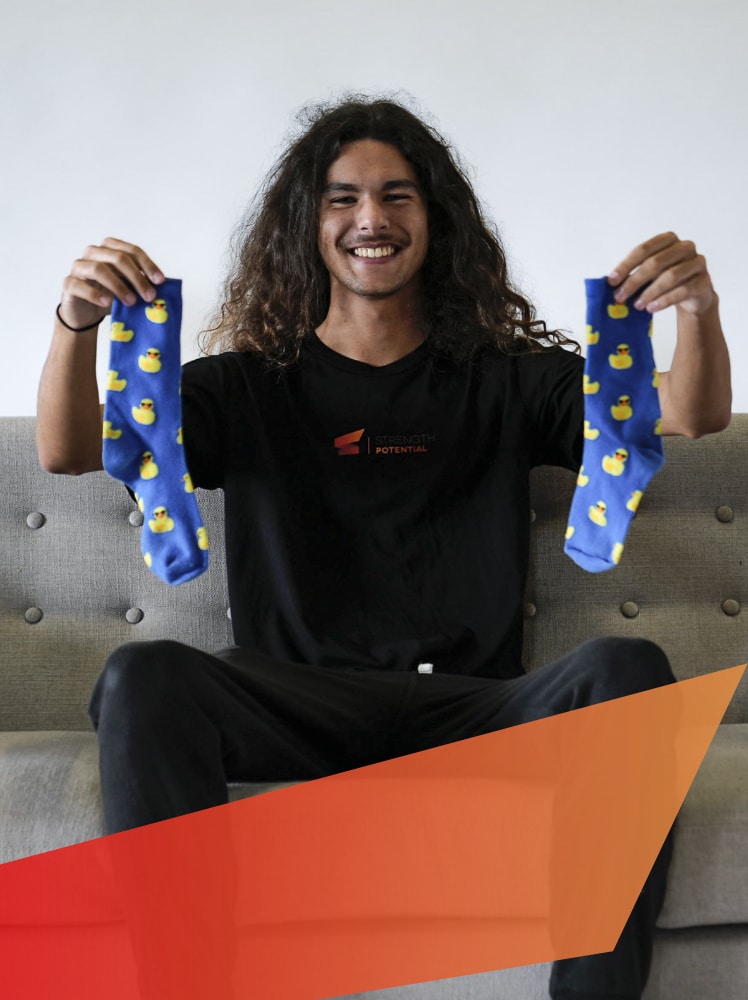 strength-potential-mentor-and-support-worker-Johan-Kruger-funny-portrait-holding-blue-and-yellow-duck-socks